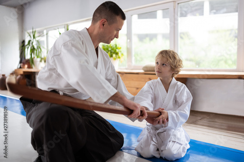 Blonde-haired little boy listening to his aikido teacher