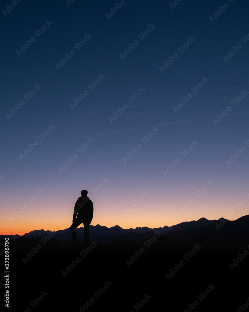 A man looks at the sun rising from the top of a mountain