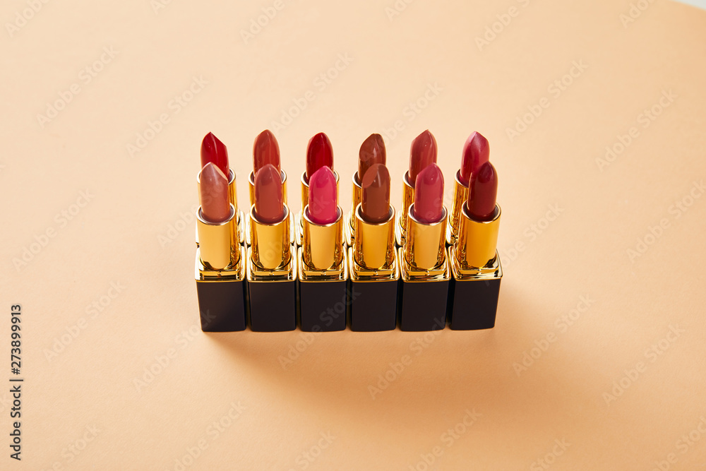various red shades of lipstick in tubes on beige various red shades of lipstick in tubes on beige