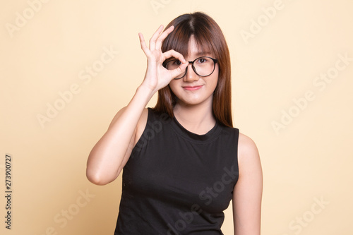 Beautiful young Asian woman show OK sign over her eye.