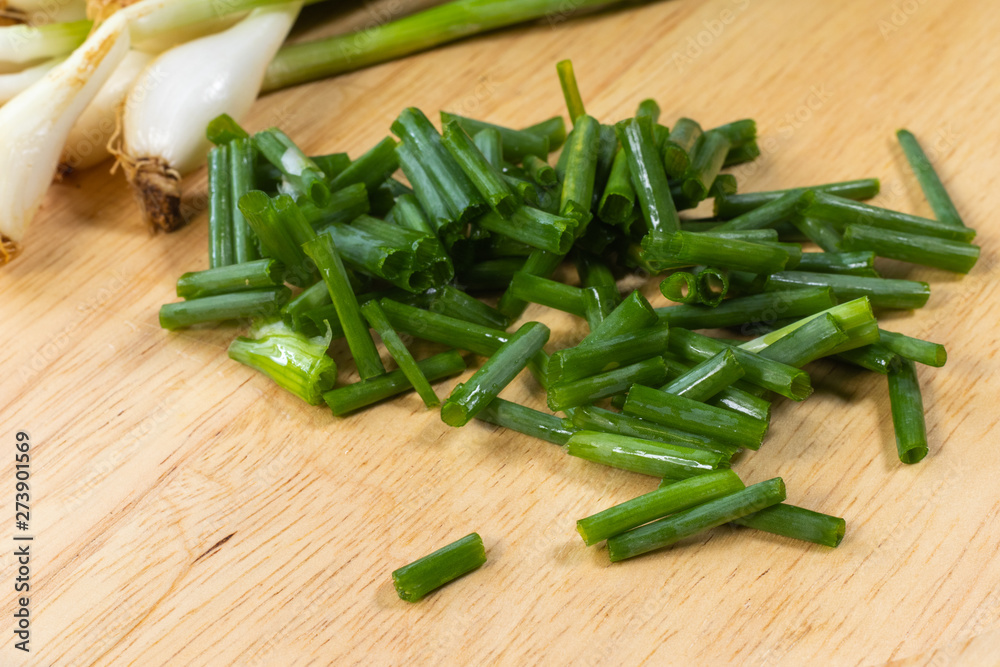 chopped of fresh scallion or spring onions on wooden board chopped of fresh scallion or spring onions on wooden board