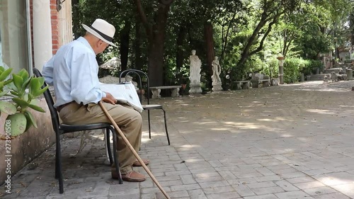 The elder reads the press.  senior man reading newspaper while sitting in the park
