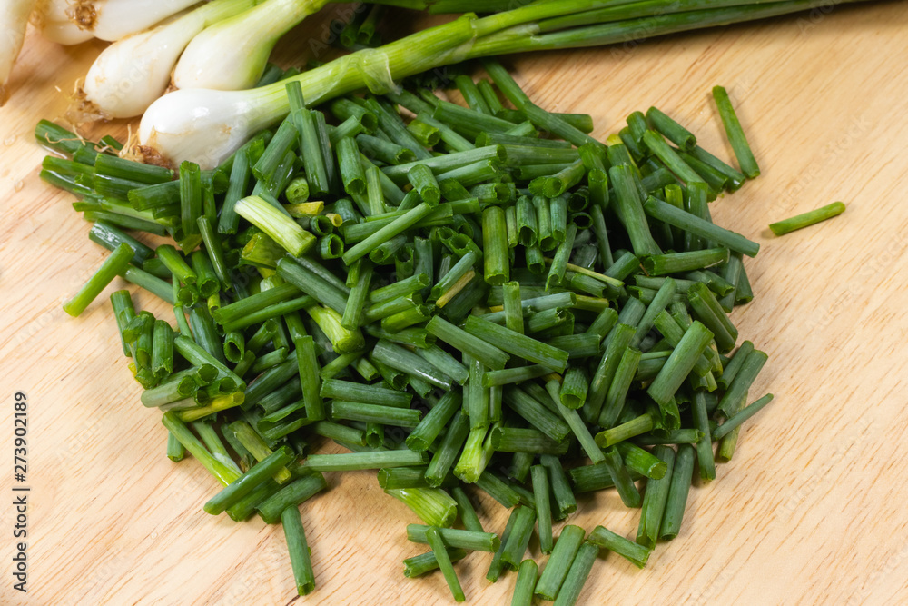 chopped of fresh scallion or spring onions on wooden board chopped of fresh scallion or spring onions on wooden board