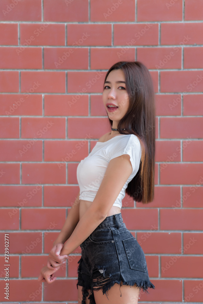 Foto Stock Portrait of beautiful asian chic girl pose for take a picture on  brick wall background,Lifestyle of teen thailand people,Modern woman happy  concept,Punk rock style | Adobe Stock