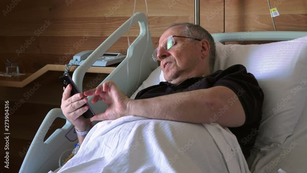 Hospital patient - elderly man lying on a special medical bed and talking on a mobile phone Hospital patient - elderly man lying on a special medical bed and talking on a mobile phone