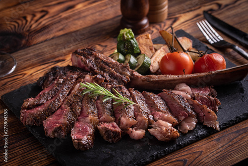 Photos grilled tomahawk ribeye steak on black stone plate