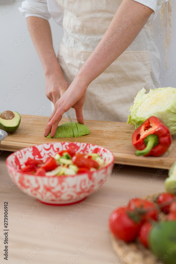 A woman makes a salad of fresh vegetables. Vegetarian, healthy food.