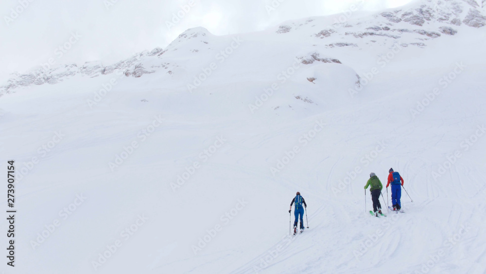 Ski resort. Three people walking upwards by the ski in a mountains