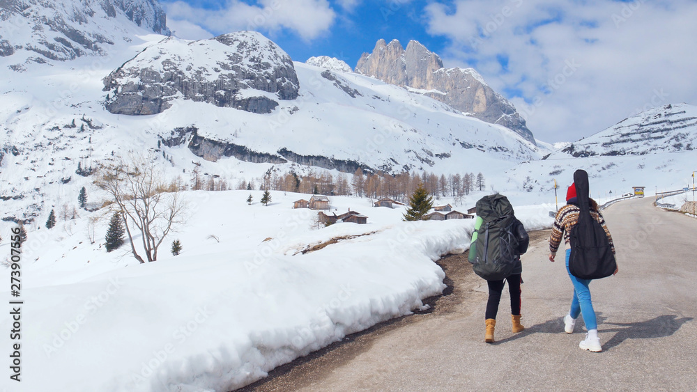 Two young women tourist traveling in Dolomites with big backpack and guitar
