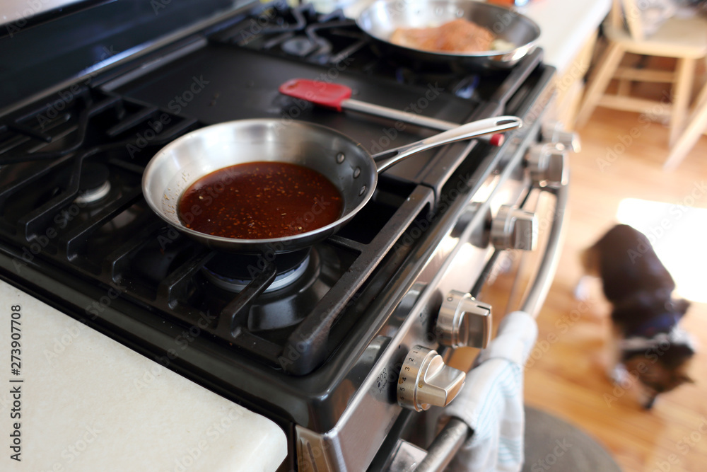 Demi glace or brown glaze cooking in a stainless steel skillet on the stove top. Demi glace or brown glaze cooking in a stainless steel skillet on the stove top.
