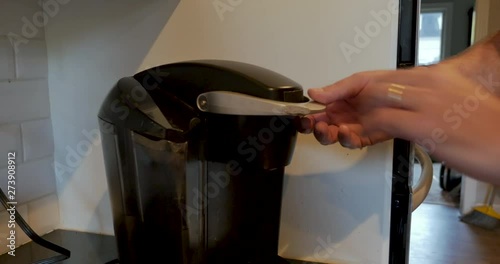 Man using a single serving pod coffee maker to brew a cup of coffee
