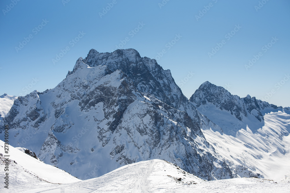 Winter mountains with snow and blue sky in nice sun day. Ski resort and sport concept. Caucasus Mountains, region Dombay. View from the top of Musa Achitara