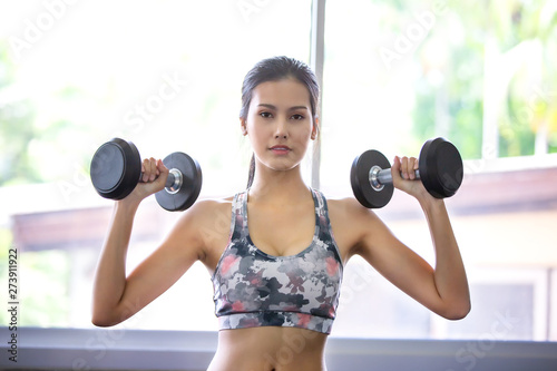 Young Woman Lifting Dumbbell or exercise In Gym