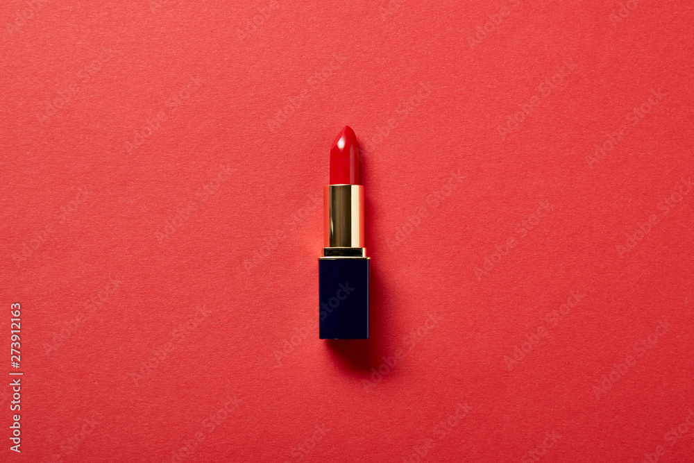 top view of single tube of red lipstick on red - obrazy, fototapety, plakaty 