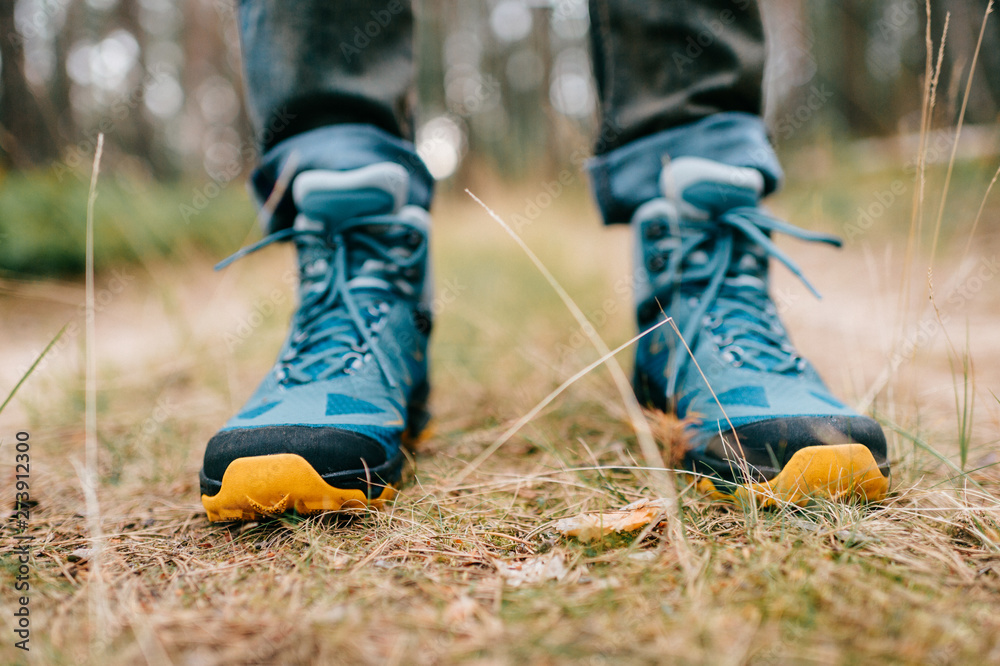 Male legs wearing sportive hiking shoes outdoor. Mens legs in trekking boots for outdoor activity Male legs wearing sportive hiking shoes outdoor. Mens legs in trekking boots for outdoor activity