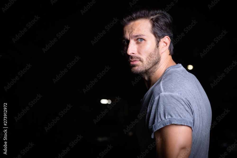 Portrait of handsome bearded man looking back outdoors at night