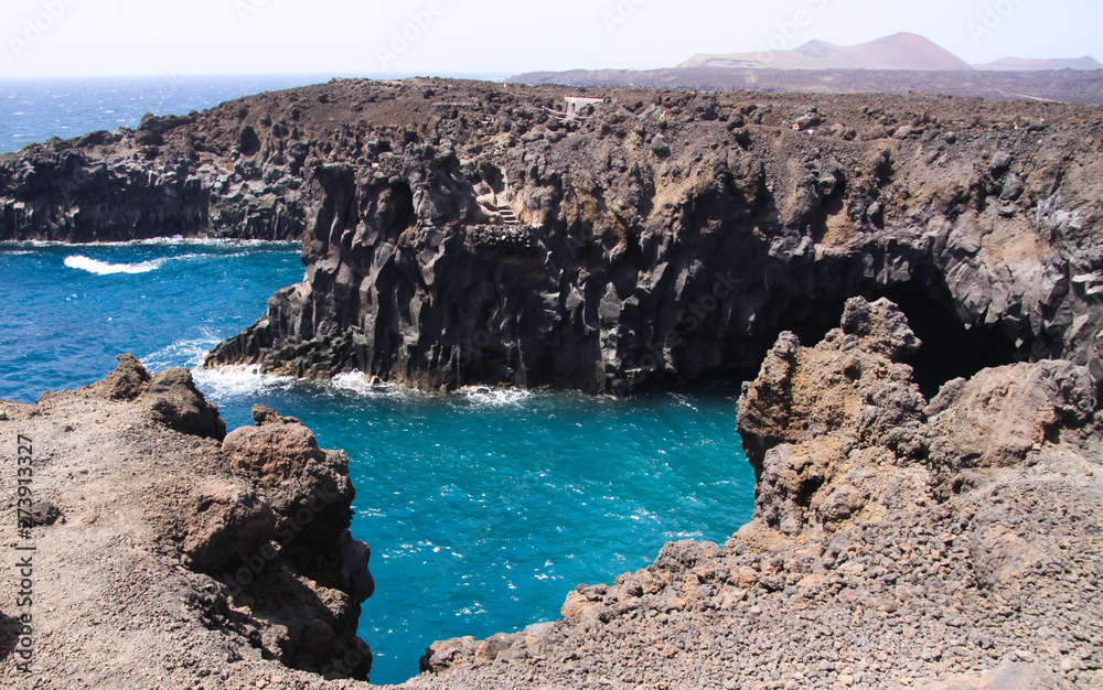 View on rugged rough coastline with sharp cliffs. lagoon with turquoise blue water, waves - Los Hervidereos, Lanzarote
