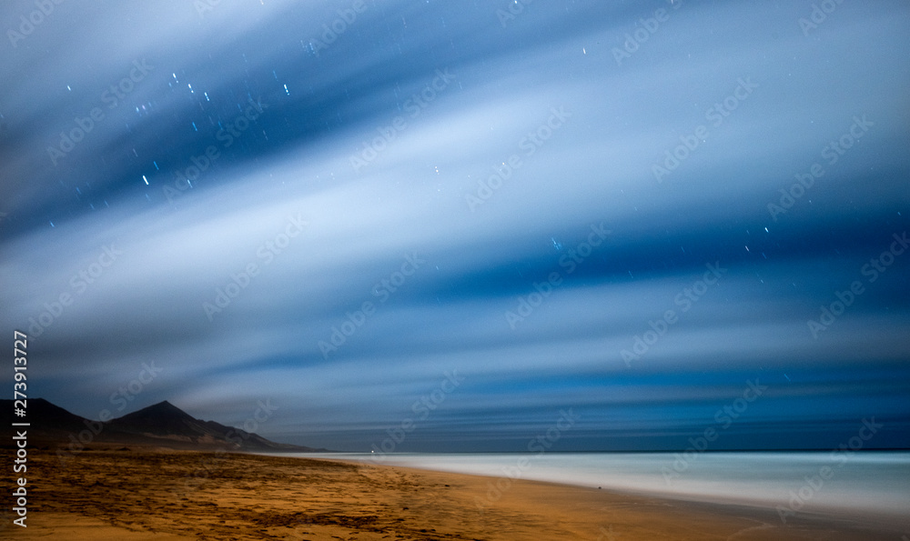 Fototapeta premium Night picture with long exposure and night star in movement - beach and mountains beautiful wild landscape for travel adventurer and alternative vacation feeling the nature