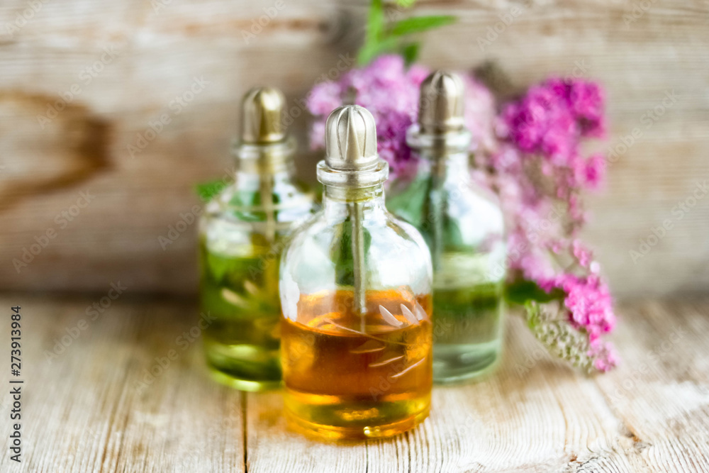 Spa perfume essential aroma oil glass bottles with flower blossoms on old wooden background Spa perfume essential aroma oil glass bottles with flower blossoms on old wooden background