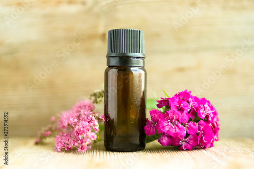 Spa perfume essential aroma oil glass bottle with flower blossoms on old wooden background