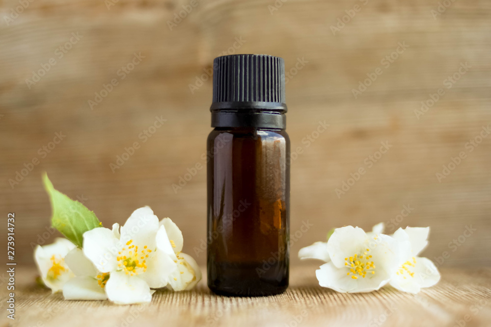 Spa perfume essential aroma oil glass bottle with flower blossoms on old wooden background Spa perfume essential aroma oil glass bottle with flower blossoms on old wooden background