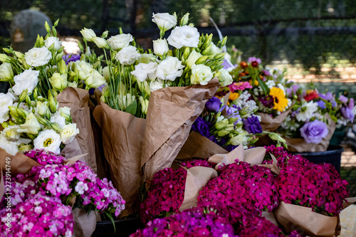 Paper-wrapped bundles of fresh summer flowers make a colorful display at a farmers market.