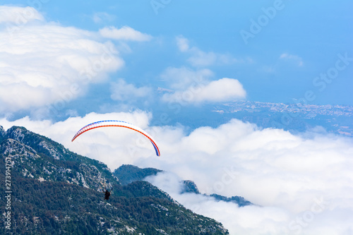 Paragliding flying in the sky over mountains and sea. Aerial view from Tahtali mountain, Turkey. Extreme sport or travel concept