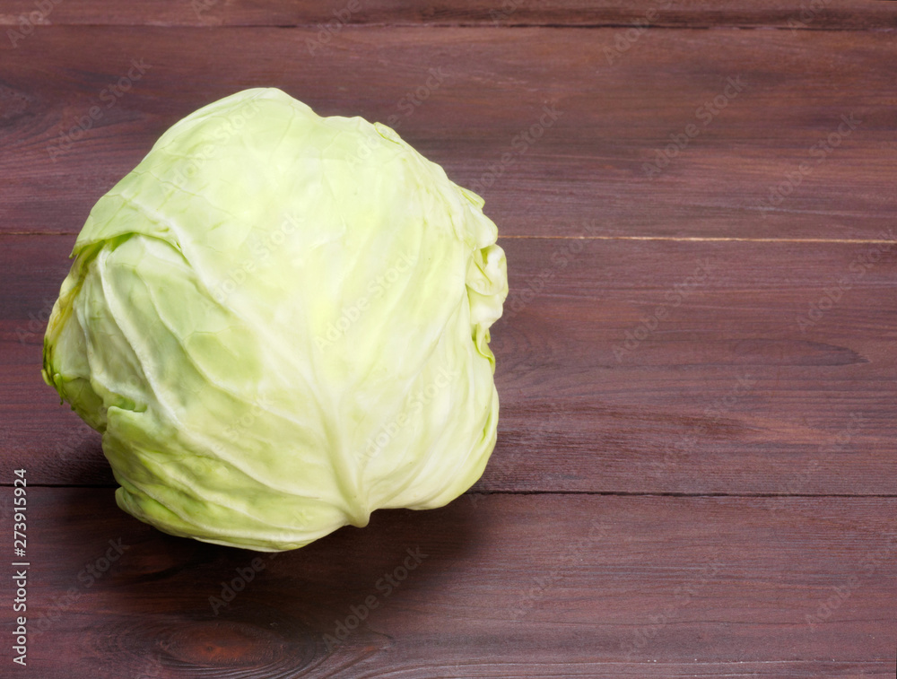 Fototapeta premium Green cabbage on a brown wooden background