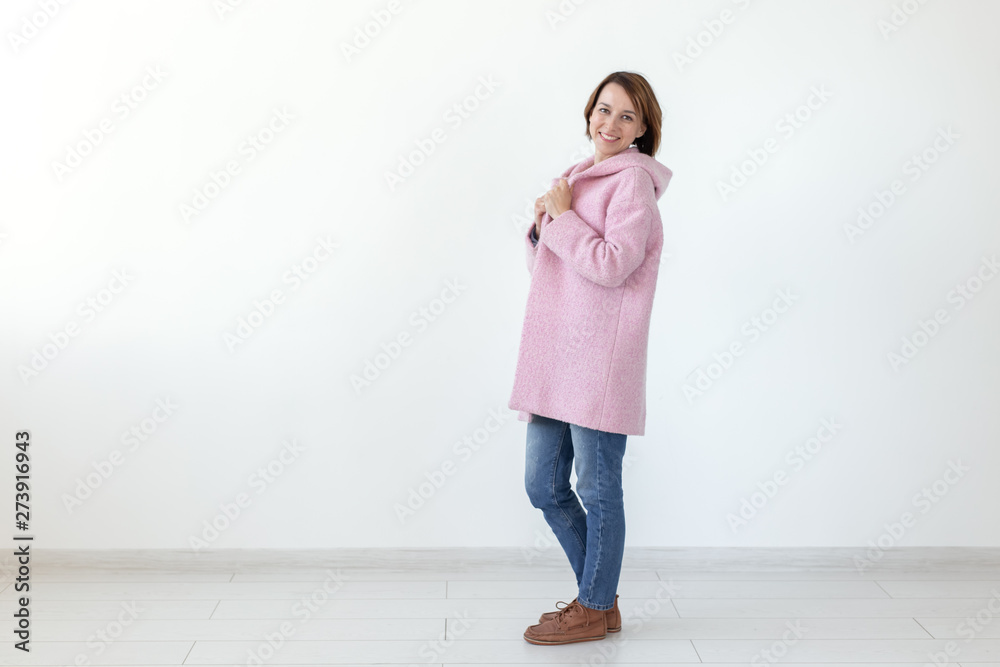 Charming young female model posing on a white background in a designer pink coat. The concept of a unique handicraft design. Advertising space, copyspace Charming young female model posing on a white background in a designer pink coat. The concept of a unique handicraft design. Advertising space, copyspace