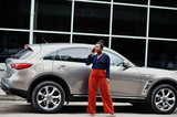 Rich business african woman in orange pants and blue shirt posed against silver suv car and speak on mobile phone.