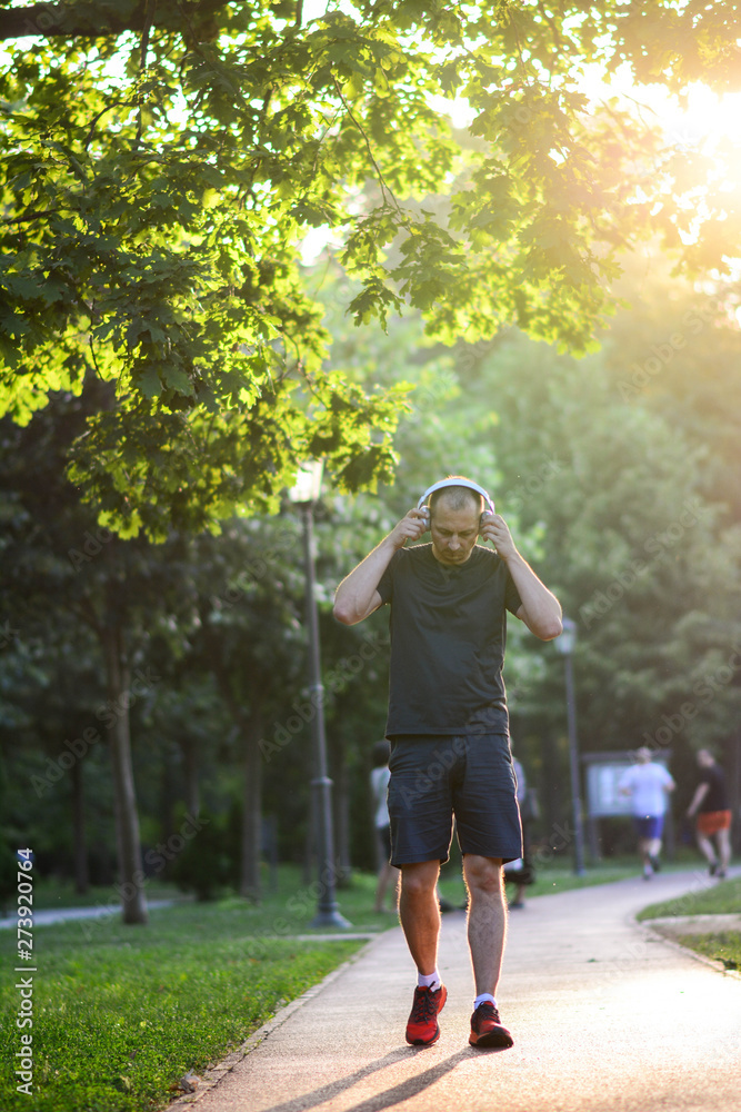 Male fitness model training outside on a warm summer day and listening to music. Sport lifestyle concept. Vertical. Male fitness model training outside on a warm summer day and listening to music. Sport lifestyle concept. Vertical.