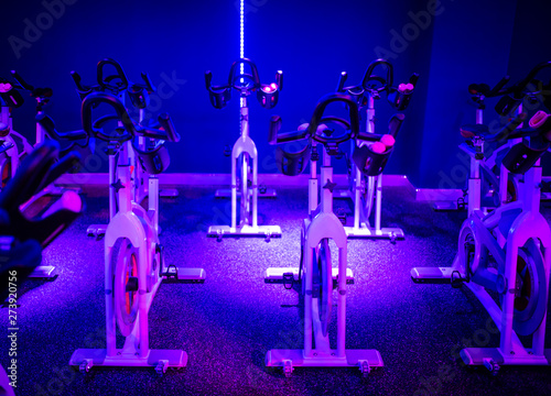 An indoor cycling dance class in a blue LED lighting room