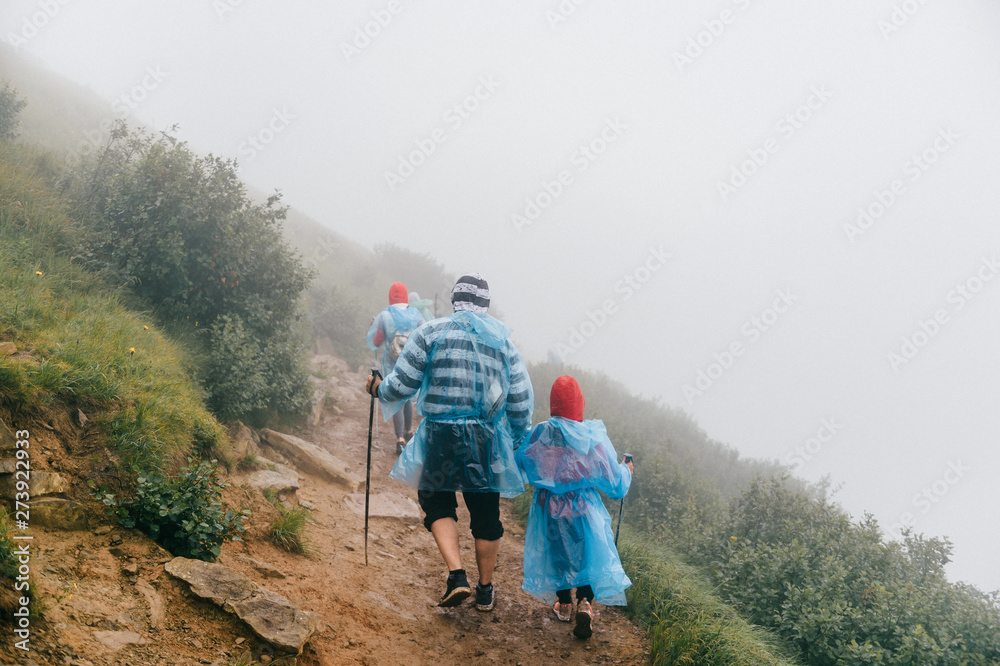 Hiking. Backpackers hiking in foggy mountains. Mountain trekking. Men with backpacks on trek.
