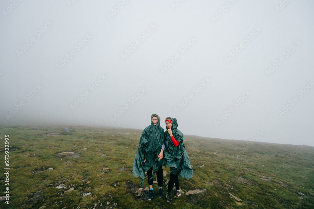 Happy female couple hikers posing in foggy mountains.