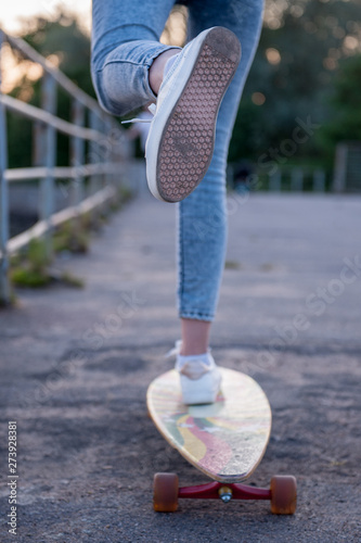 Girl with longboard wearing sneakers shoes in urban style