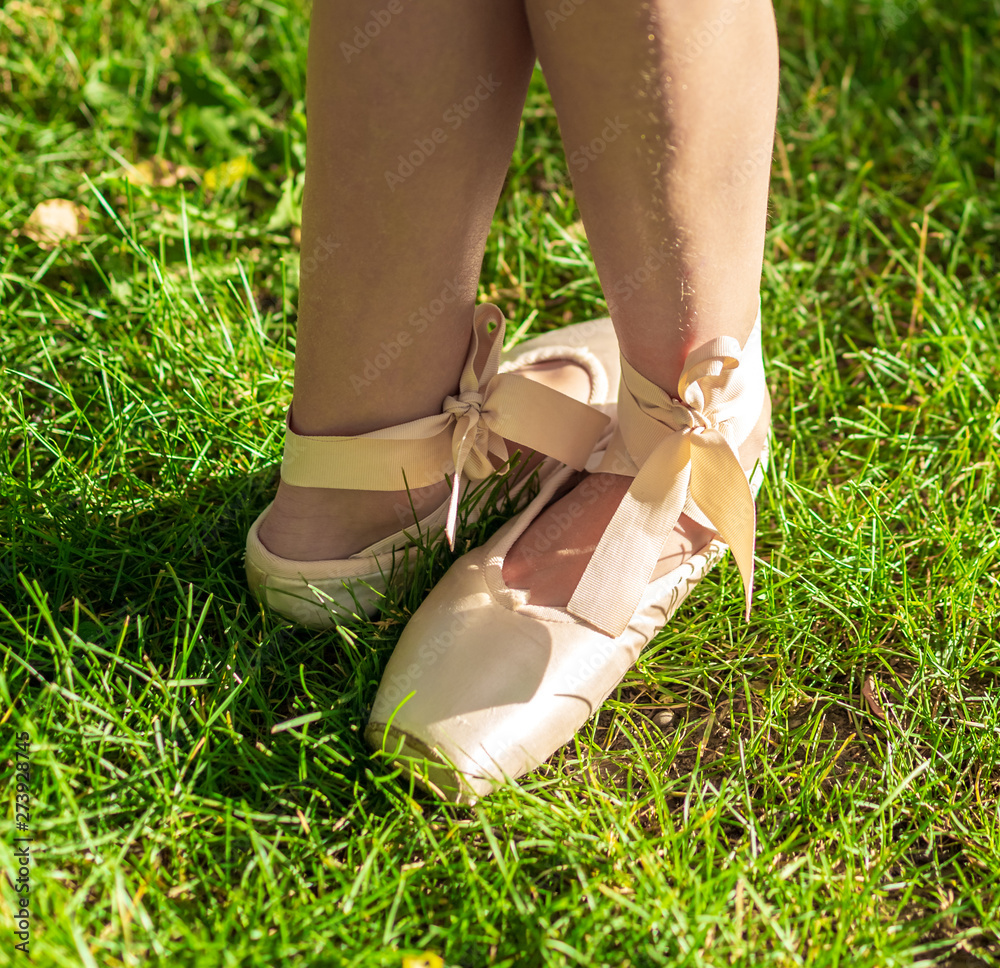 Girl's feet in Pointe on the grass in the sun, ballet