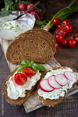 Preparation of summer sandwiches cottage cheese with green onions, radishes and tomatoes. keto diet ,healthy lifestyle. fresh fruit.On a dark background .wood boards