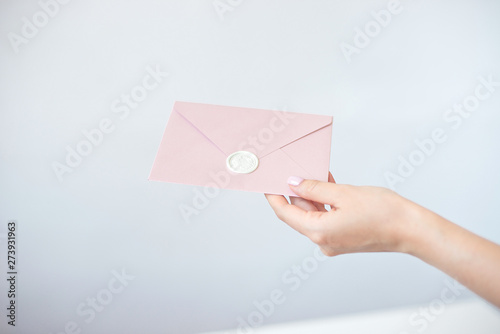 Close-up woman with slim body holding in hands the invitation card blue pink color square shape envelope card