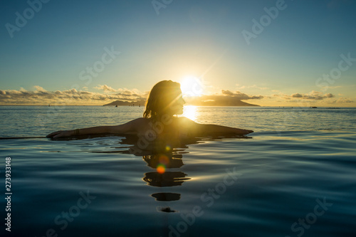 French Polynesia, Tahiti, Papeete, woman enjoying the sunset in an infinity pool photo
