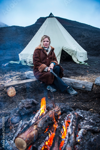 Woman in fur jacket standing before a tipi tent before the Tolbachik volcano, Kamchatka, Russia photo