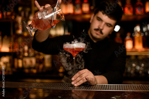Bartender with strainer preparing an alcohol drink