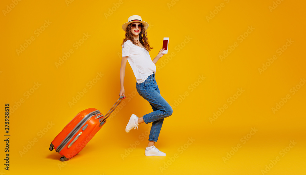 concept of travel. happy woman girl with suitcase and  passport on  yellow background