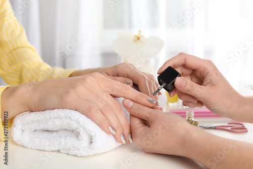Manicurist painting client s nails with polish in salon  closeup