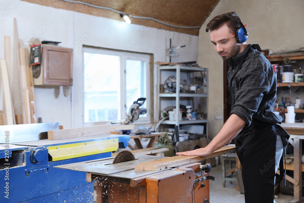 Young working man using circular saw at carpentry shop Young working man using circular saw at carpentry shop
