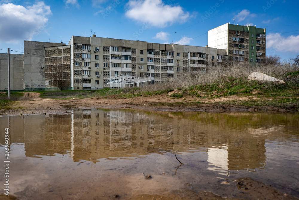 Residential building in Elista is reflected in the spring puddle. Russian cities. Travels in Russia