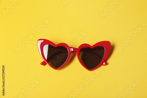 Stylish heart shaped glasses on color background, top view