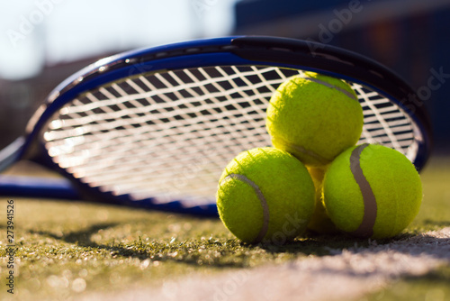Macro image of three tennis balls and racket on hard court under sunlight © speed300