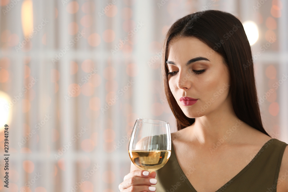 Beautiful young woman with glass of luxury white wine indoors. Space for text