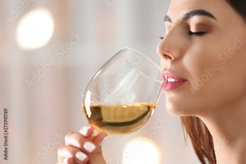 Beautiful young woman with glass of luxury white wine indoors, closeup view. Space for text