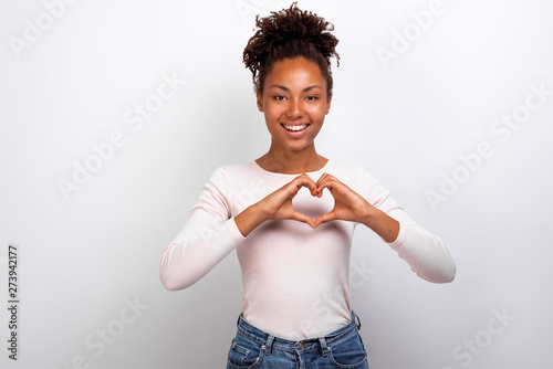 Cute woman shows a heart gesture with her fingers next her chest. Concept gesture - Image photo